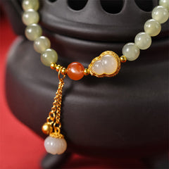 Gourd Lotus Bracelet gold filigree centerpiece with jade beads on black incense burner, red backdrop, artisanal