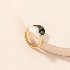 Yin Yang Adjustable Couple Ring - close-up of gold-tone yin-yang with black white enamel on textured cream prop