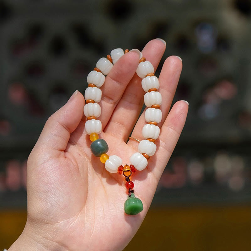 Bodhi Seed Lotus Bead Bracelet - draped over fingers, carved lotus with green gourd charm