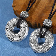 Silver Heart Sutra Pendant – two silver bi-discs showing obverse and reverse with lotus beads on blue fabric, Buddhist