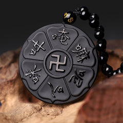 Black Obsidian Swastika Mantra Necklace - Elevated three-quarter on wood, carved mantra pendant with beaded cord, protection jewelry