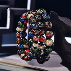 Colorful Liuli Glass Bead Luck Bracelet – Multicolor glass beads with iridescent surface hues worn on wrist with gold-tone watch, gray background lifestyle side shot