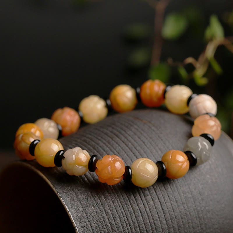 Golden Silk Jade Lotus Bracelet – Multi-tone lotus beads with black onyx spacers on dark ceramic, wealth luck jade