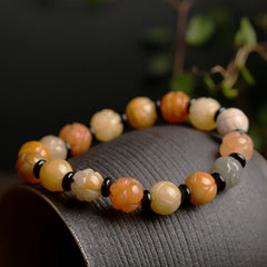 Golden Silk Jade Lotus Bracelet – Multi-tone lotus beads with black onyx spacers on dark ceramic, wealth luck jade