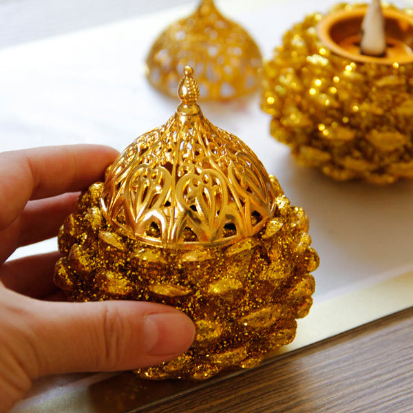 Gold Pine Cone Mini Incense Burner - Hand holding assembled unit, open base behind, golden accent