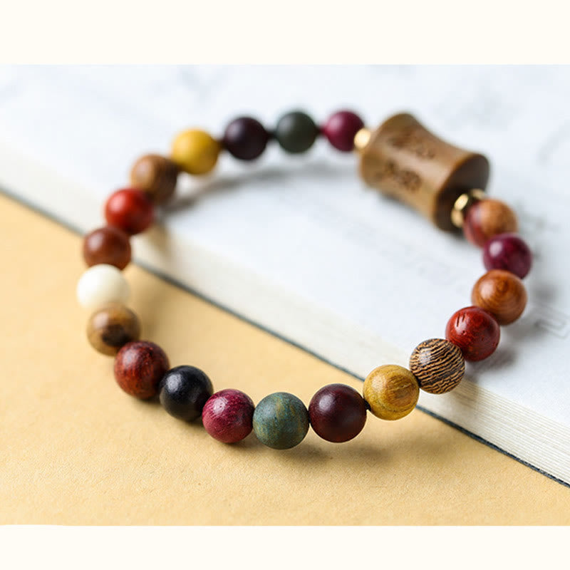 Multicolored Sandalwood Prayer Bracelet – Angled view on marble surface, carved barrel bead detail