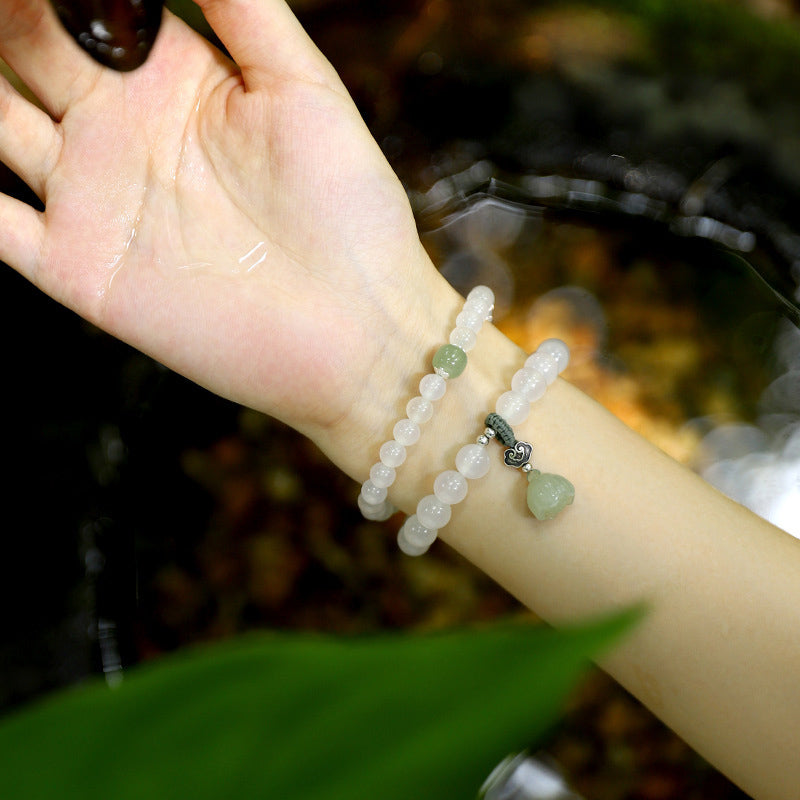 White Agate Jade Lotus Bracelet - Double-strand with green gourd charm on wrist near water, nature-inspired jewelry