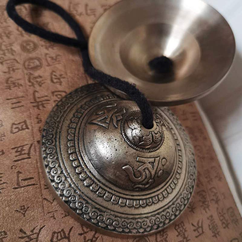 Tibetan Tingsha Bells – Close-up embossed mantra symbols and concentric borders, antique brass chimes