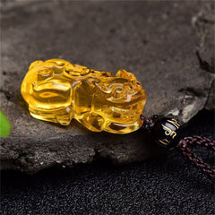 Citrine PiXiu Necklace Pendant – Yellow citrine PiXiu lying on dark stone, side angle prosperity charm