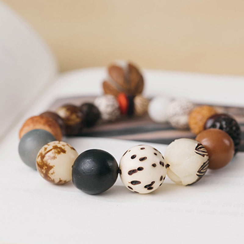 Bodhi Seed Lotus Bracelet – Low angle on fabric with botanical backdrop, earthy zen mala