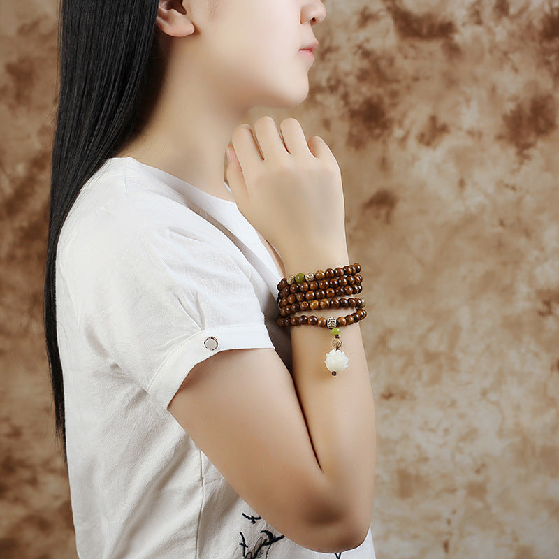 Rosewood Lotus Mala – multi-wrap bracelet worn on wrist with carved lotus pendant, spiritual protection