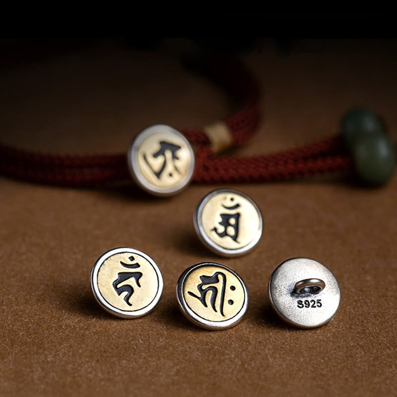 925 Silver Zodiac Natal Buddha charm collection flat lay, five interchangeable circular two-tone medallion pendants with Sanskrit seed syllables, S925 sterling silver hallmark, olive green jade bead, burgundy cord detail