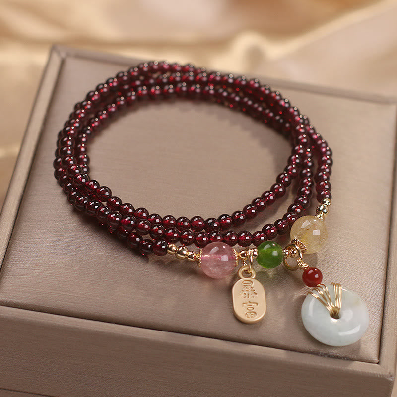 Triple-strand garnet bracelet with bai fu sudden wealth charm tag and white jade peace disc in gold wire cage setting with pink quartz green jade and citrine accent beads on gift box