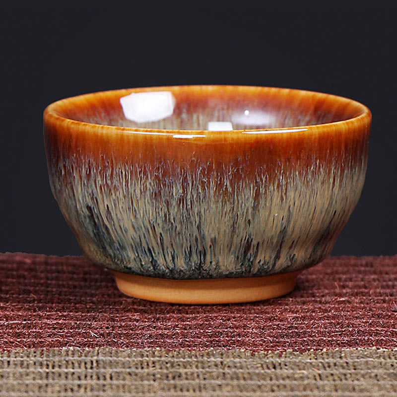 12 Zodiac Jian Zhan Teacup - hare fur glazed cup with amber-to-charcoal gradient, unglazed foot on burgundy mat