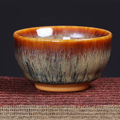 12 Zodiac Jian Zhan Teacup - hare fur glazed cup with amber-to-charcoal gradient, unglazed foot on burgundy mat