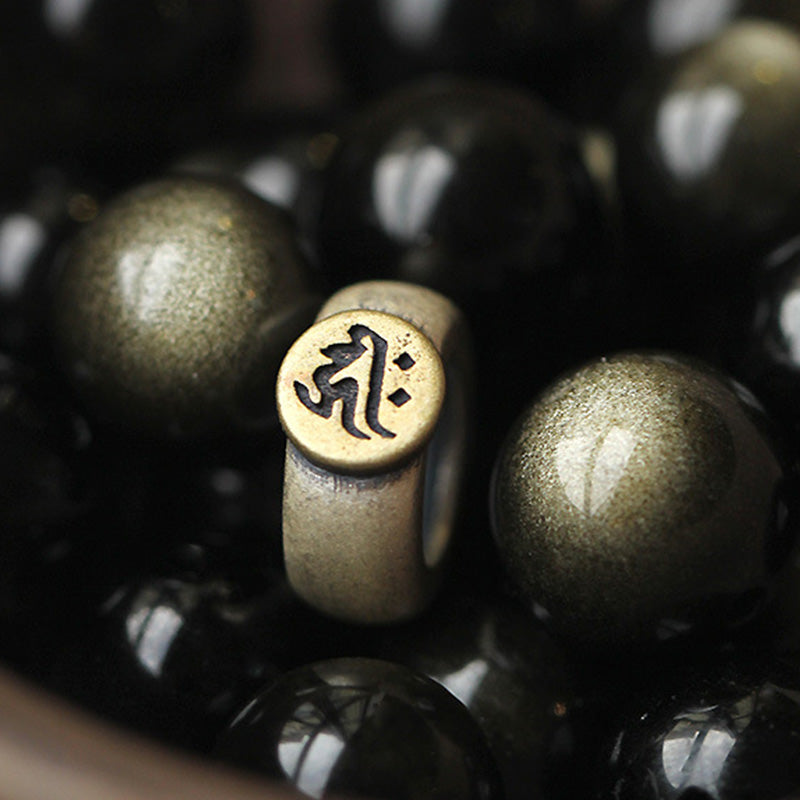 Zodiac Natal Buddha Obsidian Silver Bracelet - Extreme close-up of brass mantra bead with obsidian