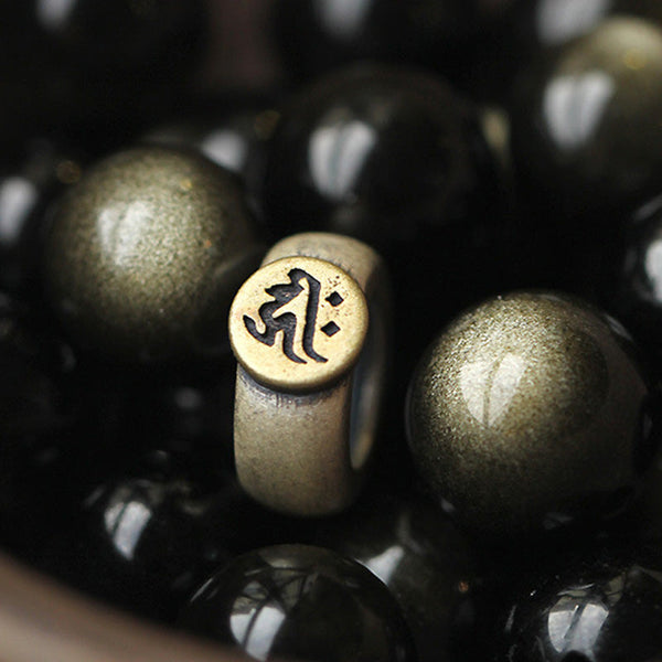 Zodiac Natal Buddha Obsidian Silver Bracelet - Extreme close-up of brass mantra bead with obsidian