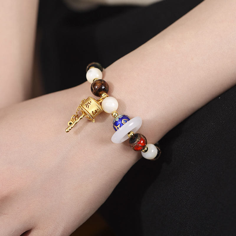 Liuli Glass Prayer Wheel Bracelet – On wrist against dark background, cloisonne bead detail