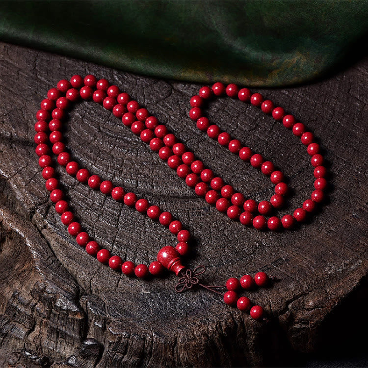 108 Mala Beads Cinnabar Bracelet – Overhead view on tree stump, red prayer necklace