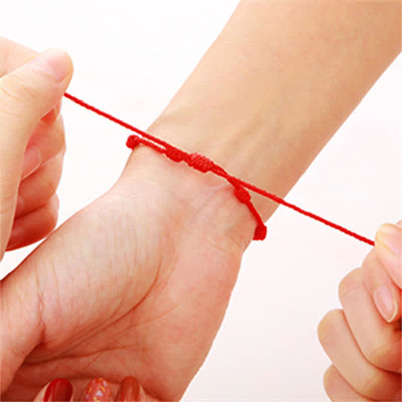 4Pcs Evil Eye Red String – Red knotted cord bracelets on white marble with literary page, flat lay