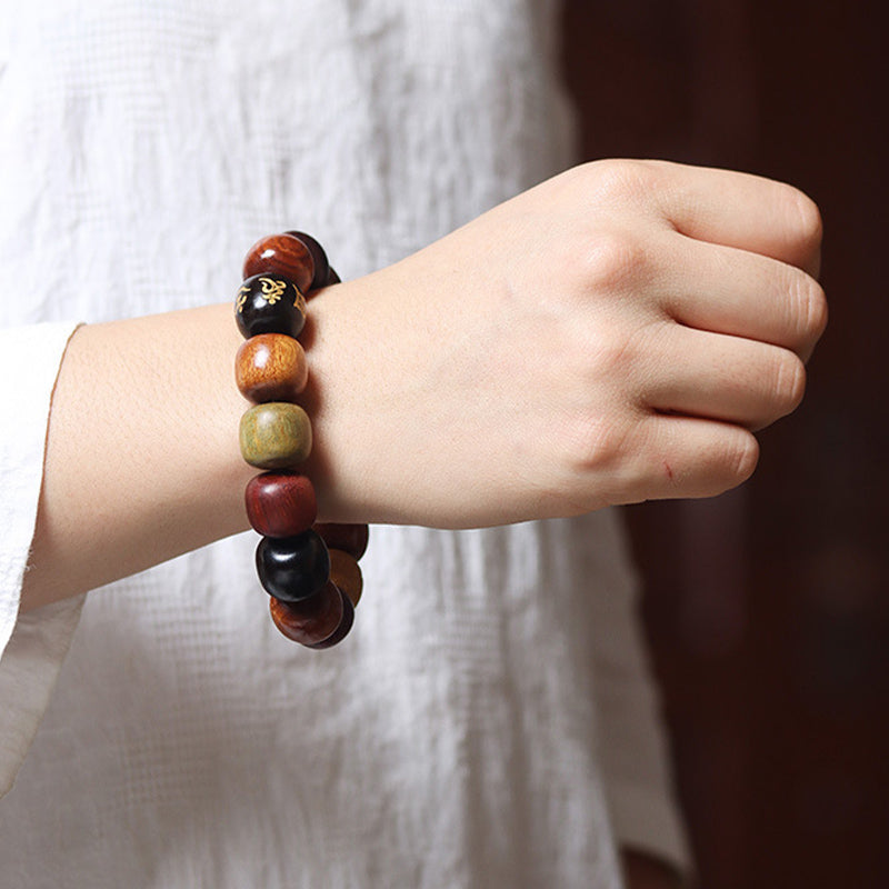 Tibetan Prayer Bracelet – worn on wrist showing gold-character ebony bead among wood tones, wooden bracelet
