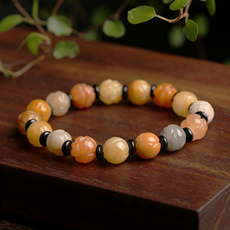 Golden Silk Jade Lotus Bracelet – Warm earth tone lotus beads with black spacers on wood with greenery, jade jewelry