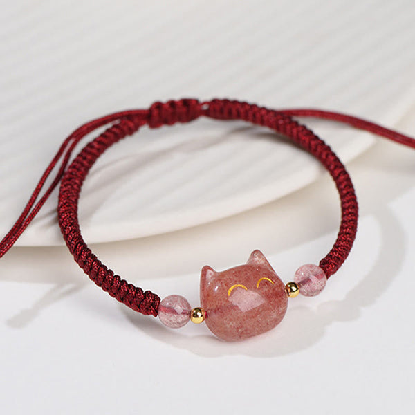 Handcrafted adjustable bracelet with strawberry quartz cat charm, gold smile details, pink crystal beads and burgundy macrame cord on white fabric