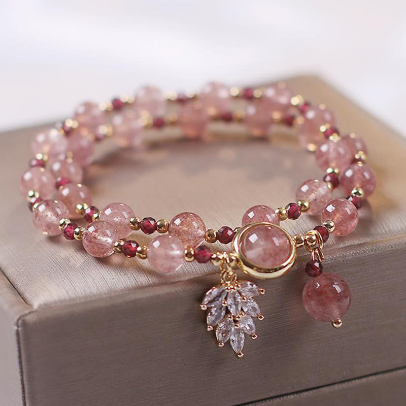 Double-strand strawberry quartz beaded bracelet with garnet red accent beads gold spacers crystal leaf charm and pink teardrop pendant on champagne jewelry box