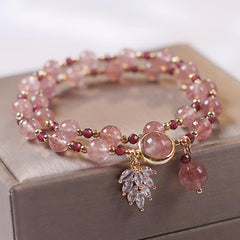 Double-strand strawberry quartz beaded bracelet with garnet red accent beads gold spacers crystal leaf charm and pink teardrop pendant on champagne jewelry box