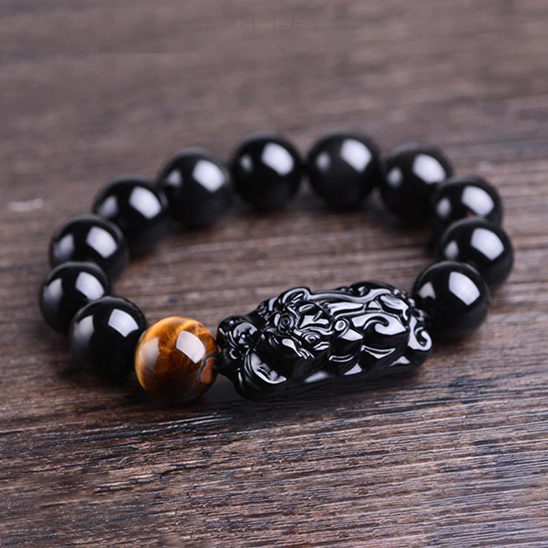 Obsidian PiXiu Tiger Eye Bracelet side view on wood grain, carved Pixiu centerpiece, feng shui protection