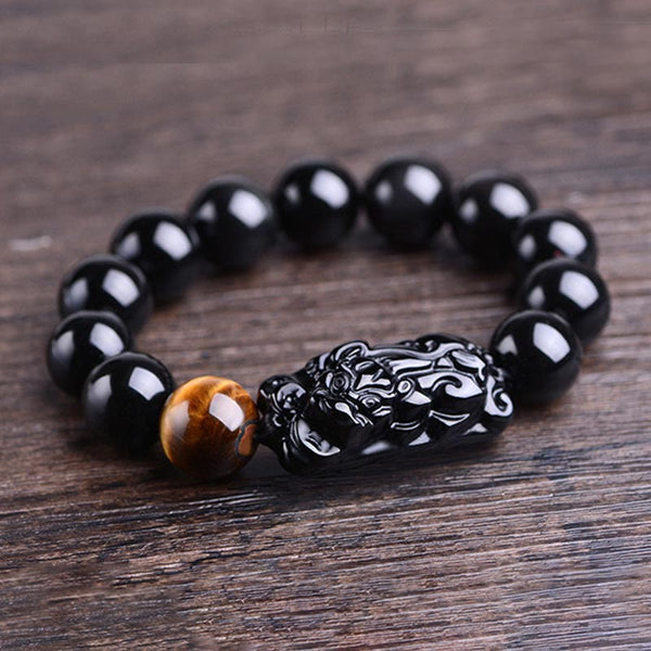 Obsidian PiXiu Tiger Eye Bracelet side view on wood grain, carved Pixiu centerpiece, feng shui protection