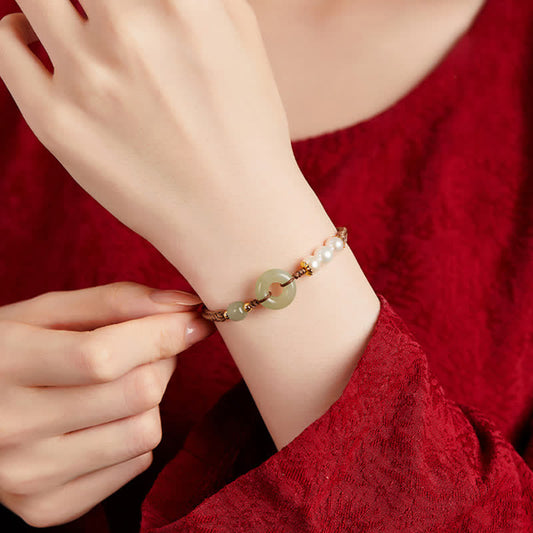Hetian Jade Pearl Peace Buckle Bracelet – jade disc and pearl bracelet worn on wrist, red fabric lifestyle photo with adjusting hand