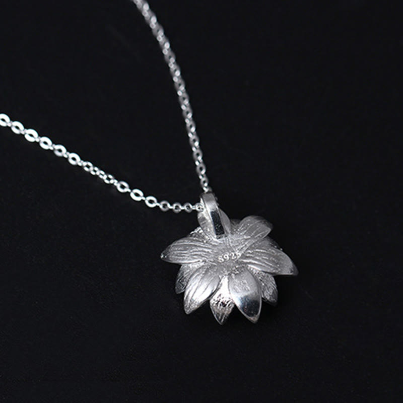 Lapis Lazuli Lotus Necklace - silver lotus with lapis center on dark wood dish, bohemian silver necklace