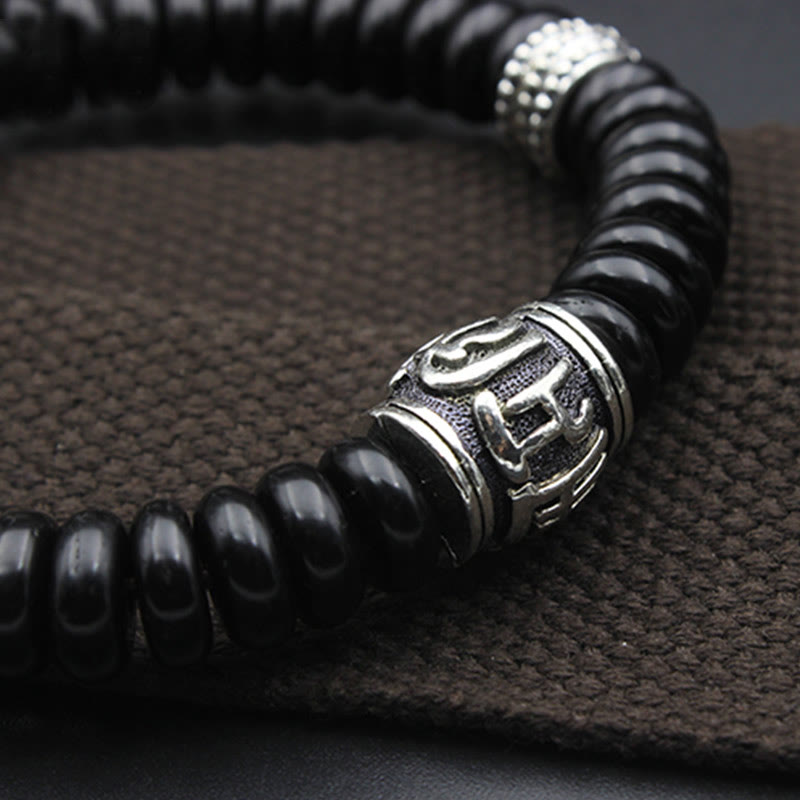 Om Mani Padme Hum Coconut Shell Bracelet – low profile shot on brown surface, silver bead detail