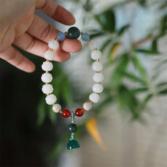 Carved Bodhi Seed Lotus Bead Peace Bracelet - held in hand with green charm, serenity