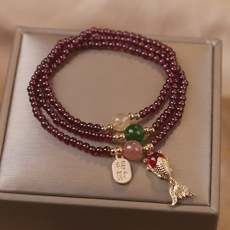 Garnet triple-strand bracelet with koi fish charm red enameled body detailed tail fins and zhao cai wealth attraction gold tag on champagne satin jewelry box presentation