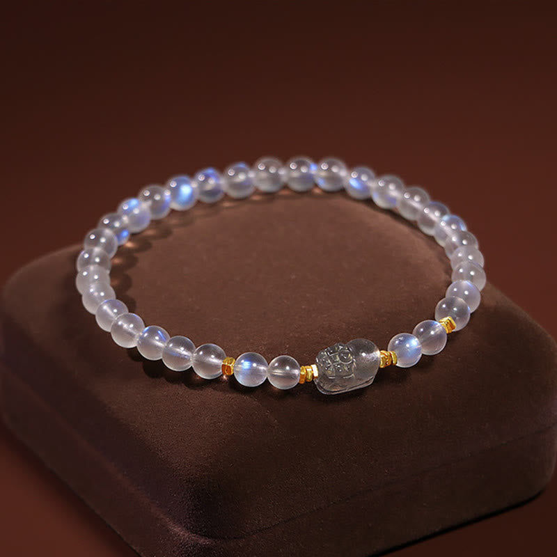 Moonstone PiXiu Bracelet – Blue-sheen moonstone bracelet with crystal PiXiu on brown display, spiritual jewelry
