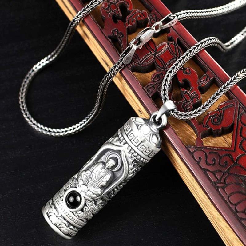 Chinese Zodiac Natal Buddha Projection Necklace – Angled view with braided chain on carved wood, ornate silver relief, heritage