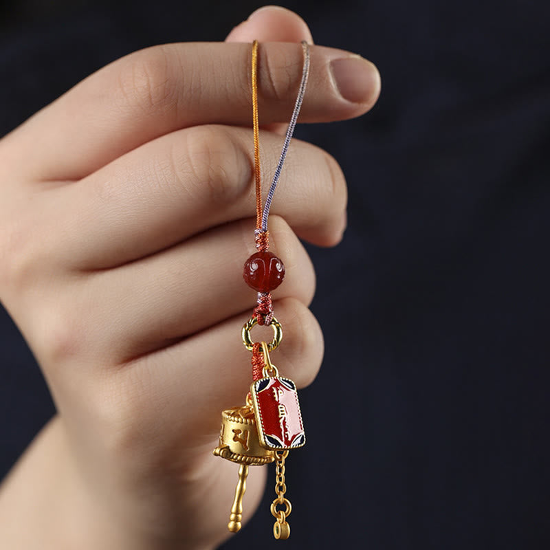Prayer Wheel Phone Charm – Handheld close-up on dark navy background, spiritual accessory