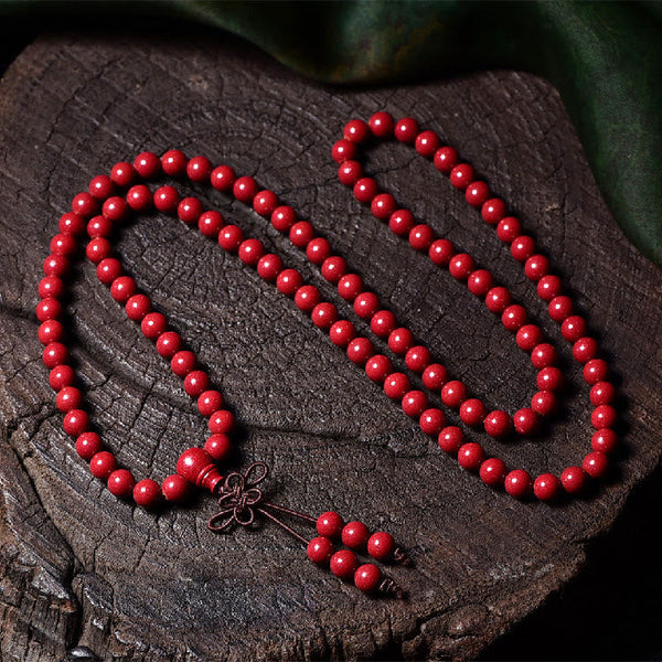 108 Mala Beads Cinnabar Bracelet – Flat lay on bark texture, 108 red carved beads