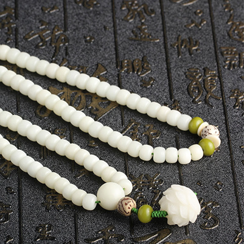 Bodhi Seed Lotus Mala - three-strand diagonal layout on carved stone, green cord and lotus detail