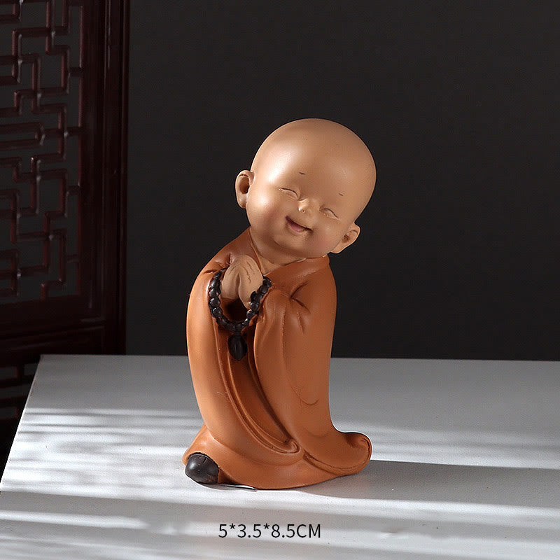 Mini Praying Monk Decor – protective plastic film being peeled from base, new product freshness