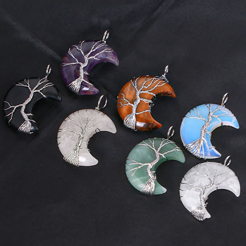 Quartz Crystal Moon Tree of Life Pendant – seven crystal variants scattered on dark fabric, collection flat lay view