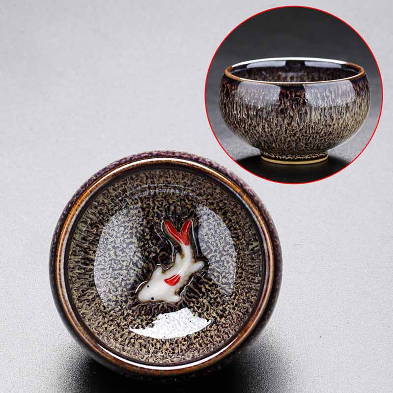 Jianzhan Koi Teacup – cup filled with tea showing submerged koi glaze, tea ware