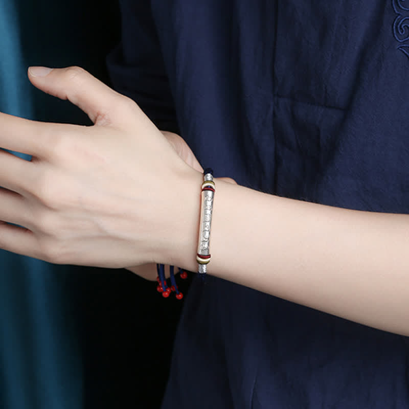 Om Mani Padme Hum Red String Bracelet – Silver mantra cylinder on blue cord worn at wrist