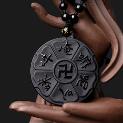 Black Obsidian Swastika Mantra Necklace - Macro on ceramic hand, swastika center with six mantra syllables, obsidian talisman