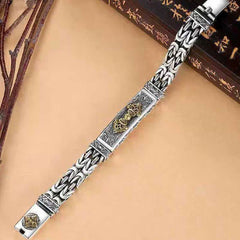 Vajra Dorje Copper Balance Bracelet - twisted braided copper chain bracelet with gold-tone ornate central medallion, heavy woven curb chain links, diagonal flat lay on warm beige surface with rustic props