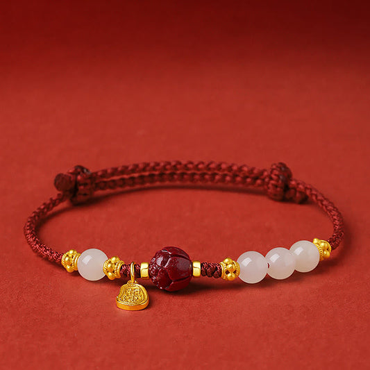 24K Gold Jade Cinnabar Lotus Bracelet – Red braided cord with white jade beads, gold lotus spacers and carved cinnabar bead on red background