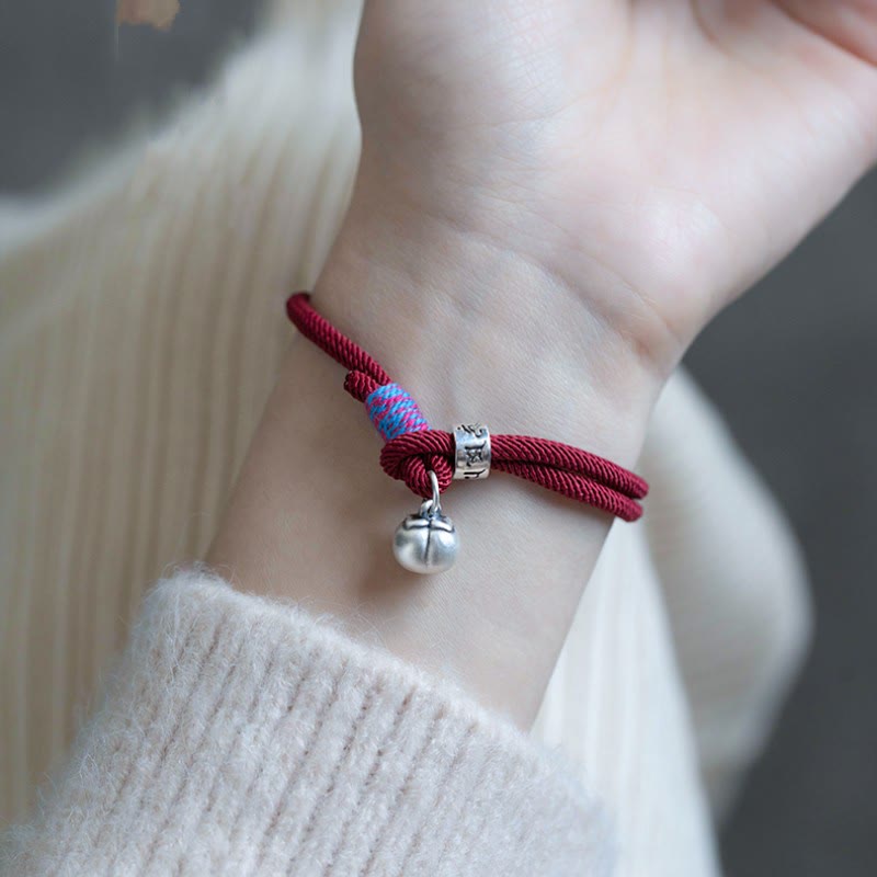 Om Mani Padme Hum Bracelet - Burgundy cord worn on wrist with silver persimmon charm, lifestyle styling