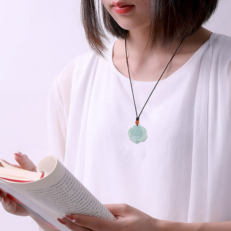 Lotus Pattern Jade Prosperity Necklace - lifestyle shot with book, jade pendant on black cord